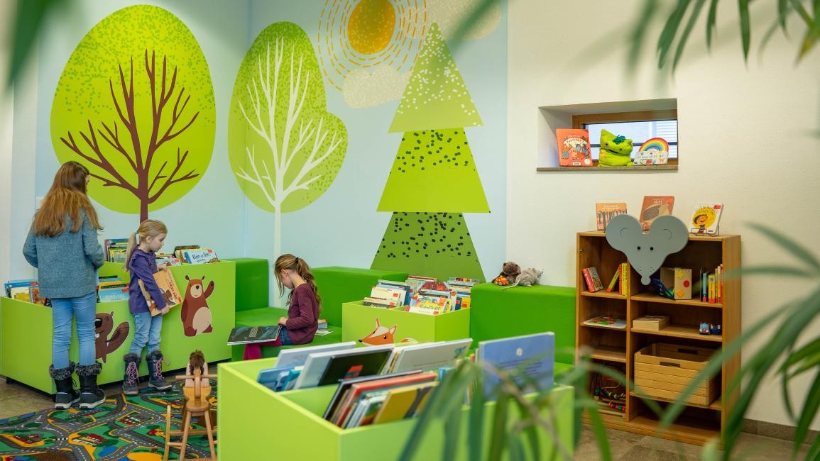 Bilderbuchecke Bilderbuchecke, drei Kinder schauen Bilderbücher an