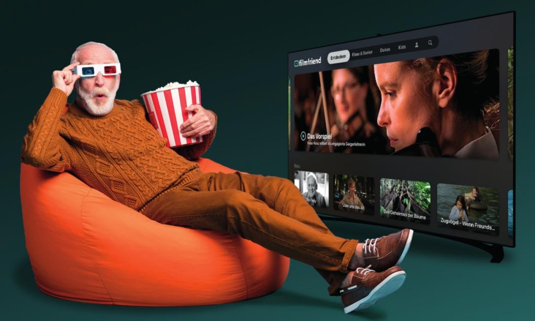 Älterer Herr in SItzsack mit Popcorn und Brille, Bildschirm rechts